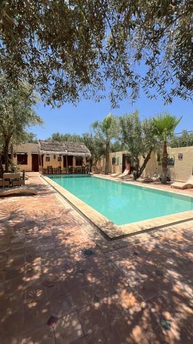 a large swimming pool in a yard with trees at Oloft in Marrakesh