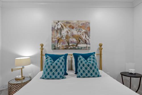 a bedroom with a bed with blue pillows and a painting at Downtown Fairhope Cottage in Fairhope