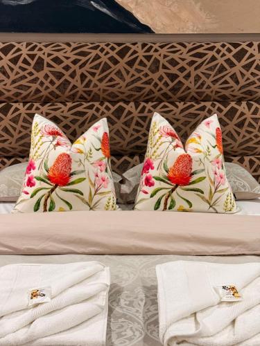 a bed with four pillows on top of it at Amira Boutique Villa in Empangeni
