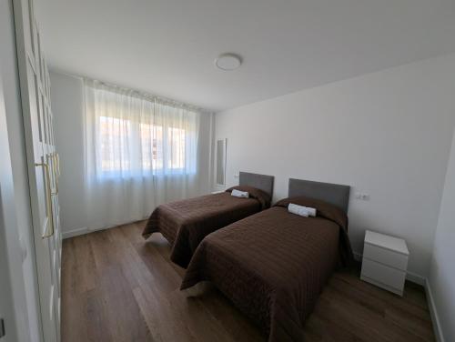 a room with two beds and a window at Alojamientos Bahia de Santoña 4 in Santoña