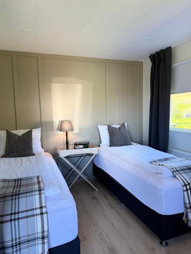 a bedroom with two beds and a table with a lamp at Granastaðir Guesthouse in Granastaðir
