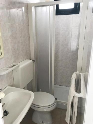 a white bathroom with a toilet and a shower at Camping Porto Miggiano in Santa Cesarea Terme