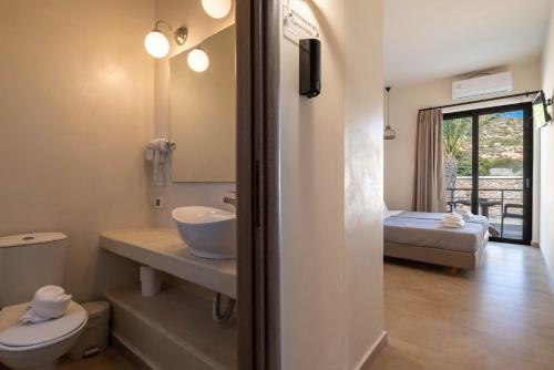 a bathroom with a sink and a toilet and a bed at Prasonisi Lighthouse Asimenis in Prasonisi