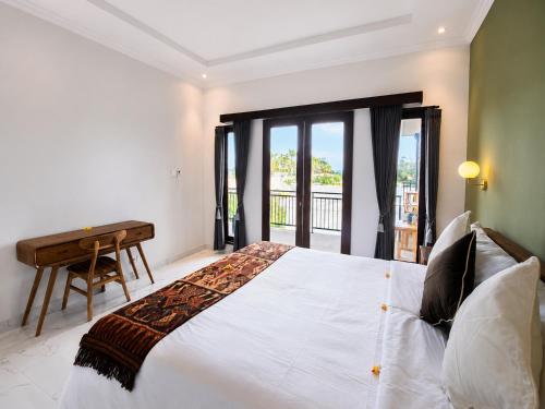 a bedroom with a bed with a desk and a window at Padmasari Guest House in Canggu