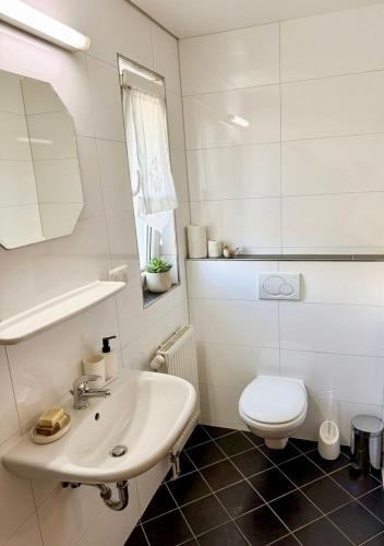 a white bathroom with a sink and a toilet at Pension Rialto in Staufenberg