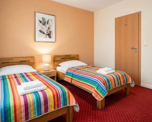 two beds in a hotel room with a colorful blanket at Pension Rialto in Staufenberg