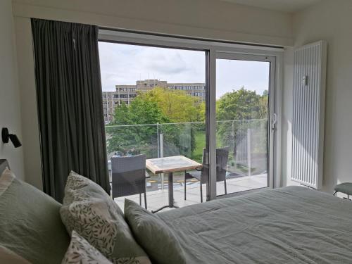 a bedroom with a bed and a balcony with a table at Driemaster, Stijlvol appartement met uitzicht op jachthaven en privé parking, centrum Oostende in Ostend