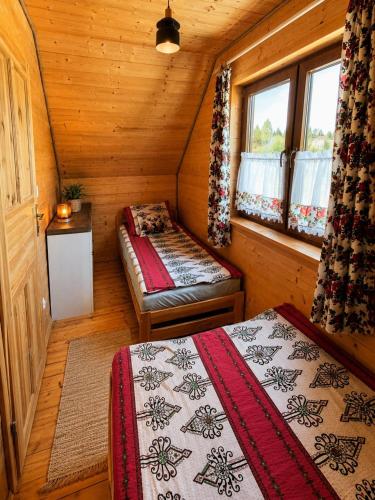 a small room with two beds in a cabin at Osada Zawóz domki z balią jacuzzi i sauną nad Jeziorem Solińskim in Zawóz