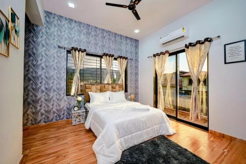 ein Schlafzimmer mit einem großen weißen Bett und Fenstern in der Unterkunft II EMPYREAN STAYS II SU CASA VILLA II 4BHK II AC II PRIVATE POOL Il in Lonavla