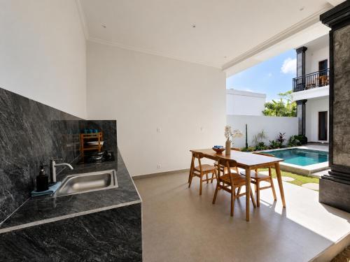 a kitchen and dining room with a table and a sink at Padmasari Guest House in Canggu