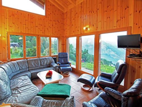 uma sala de estar com um sofá, cadeiras e janelas em Chalet Alpina offers great views em La Tzoumaz