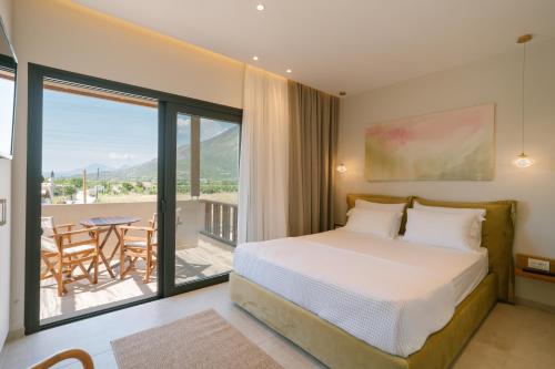 a bedroom with a bed and a balcony with a table at Atman Eco Lodge in Gliki