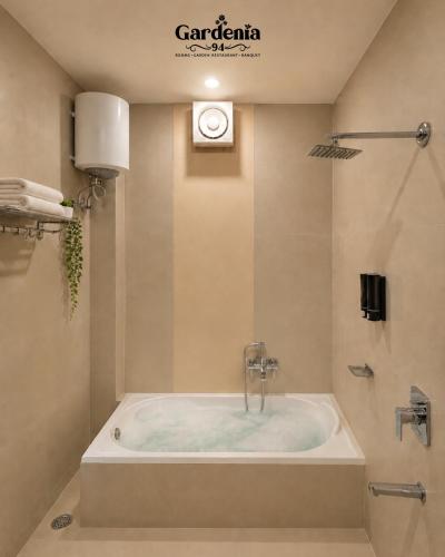 a bath tub in a bathroom with a clock on the wall at Hotel gardenia inn in Gwalior
