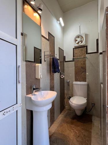 a bathroom with a white sink and a toilet at Dalipfarm River View Guestroom in Surajpur