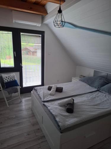 a bedroom with a bed and a chair and windows at Őrségi Csónakház in Hegyhátszentjakab