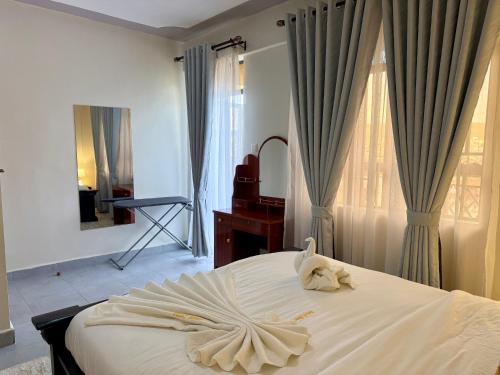 a bedroom with a white bed with a towel on it at UrbanHive Naivasha Townhouse in Naivasha