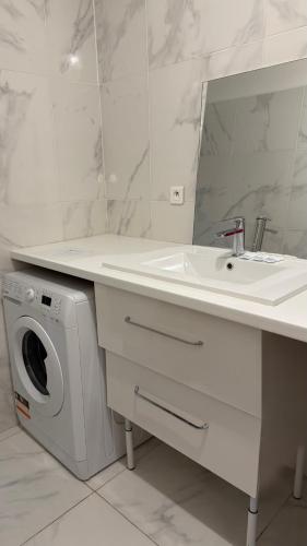 a bathroom with a sink and a washing machine at Hotel Le Bleu Marine in Saintes-Maries-de-la-Mer