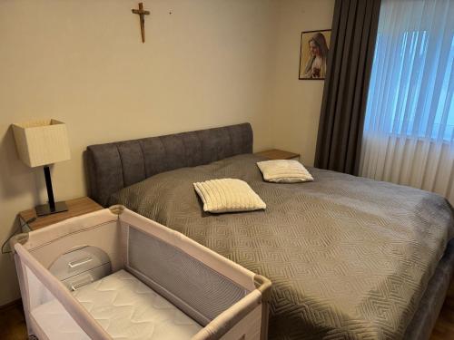 a small bed in a bedroom with a cross on the wall at Apartman Provo in Široki Brijeg