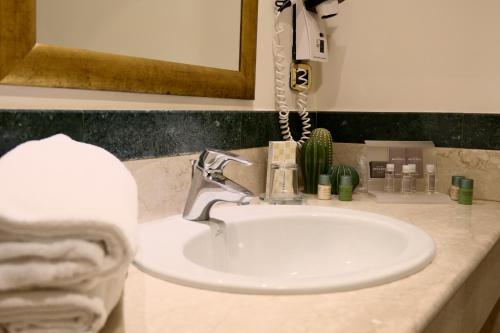a white sink in a bathroom with a phone at Minerva Resort Hotel in Paestum