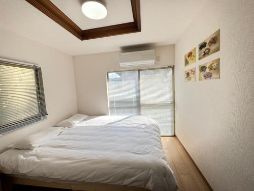 a bedroom with a white bed and a window at 羽憩館 Hakeikan KIX in Izumi-Sano