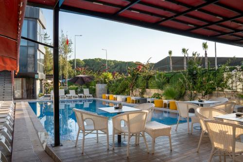a patio with tables and chairs next to a pool at Velaris Boutıque Hotel in Belek