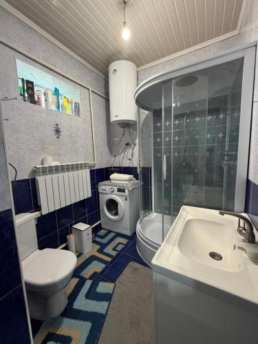 a bathroom with a toilet sink and a washing machine at Son kol Keng suu guesthouse in Keng-Suu