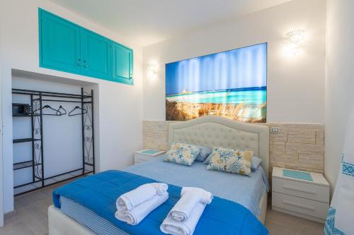 a bedroom with a blue bed with towels on it at Appartamento La Pelosa in Stintino