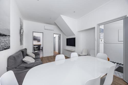 a white dining room with a white table and chairs at A Lodge in Blue in Aveiro