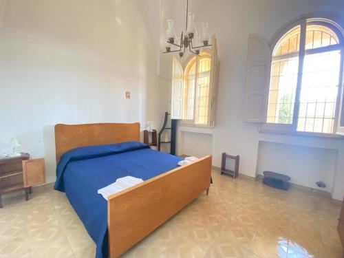 a bedroom with a bed with blue sheets and two windows at Salento mare in Casalabate