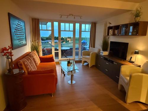 a living room with a couch and chairs and a television at Ferienwohnung De Kraan in Dorum-Neufeld