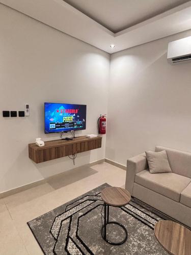 a living room with a couch and a tv on a wall at شقق حديثة موثثة in Dammam