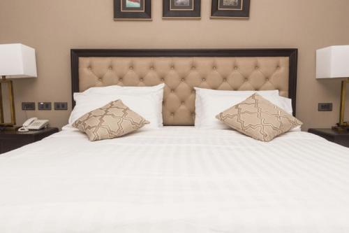 a large white bed with two pillows on it at Rizona Hotel-Narok in Narok
