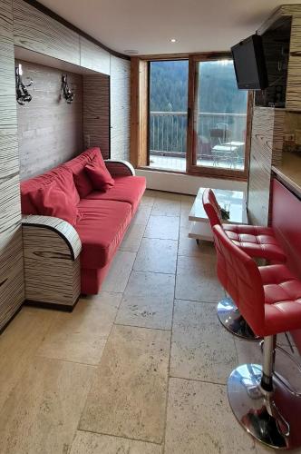 a living room with a red couch and a tv at Appartement l'Ariondaz in Courchevel