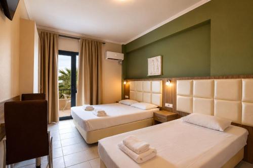 a hotel room with two beds and a window at Jason Apartments in Paralia Katerinis