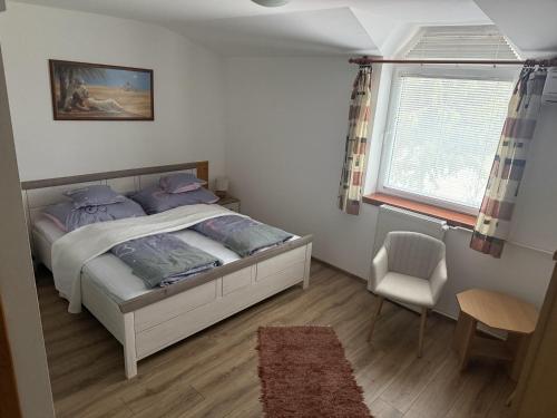 a bedroom with a bed and a chair and a window at Park Hédervár in Hédervár