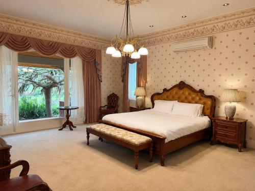 a bedroom with a large bed and a chandelier at Oak Hill House - Chirnside Park in Wonga Park