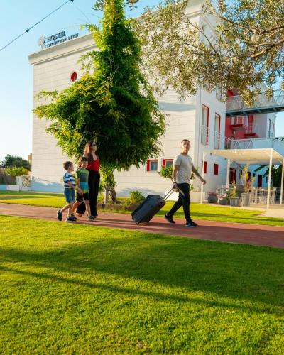 a group of people walking down a sidewalk with luggage at Glemerald Hostel in Pula