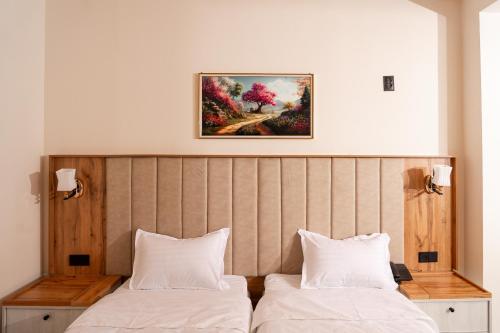 a bedroom with two beds and a painting on the wall at Gulshan Hotel in Urganch