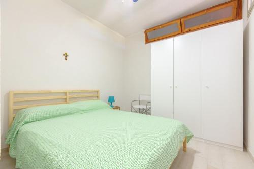 a bedroom with a bed with a green comforter at Piccola Baia in Scopello