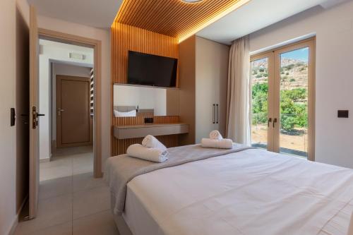 a bedroom with a large white bed and a television at Latsis Suites in Plytra