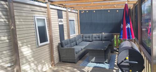 a patio with a bench and a table and two umbrellas at Chalet Lauwersoog mét airco! in Lauwersoog
