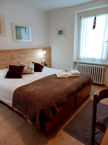 a bedroom with a large bed with two towels on it at Hotel Villa Milano in Peio Fonti
