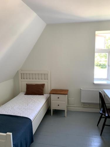 a bedroom with a bed and a table and a window at Lilla Skolhuset i Ingelsträde in Höganäs