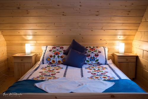 1 cama en una habitación con paredes de madera y 2 lámparas en Borowikowe Zacisze drewniane domy z dostępem do balii i sauny, en Falsztyn