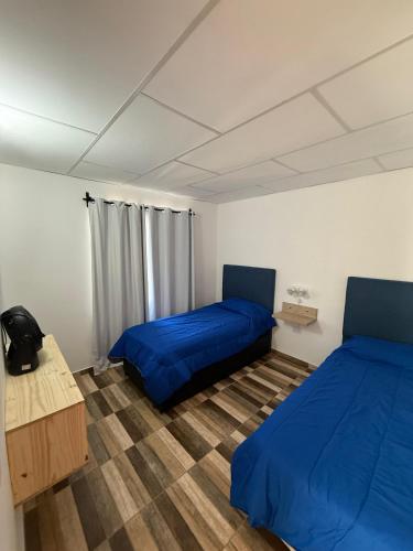 two beds in a room with blue sheets at Colibrí in Merlo