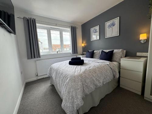 a bedroom with a bed with blue pillows and a window at Stanley Cottage in Herne Bay