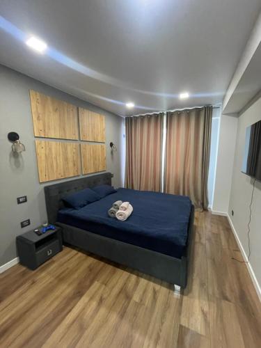 a bedroom with a bed with blue sheets and wooden floors at Alba Iulia Residence in Chişinău