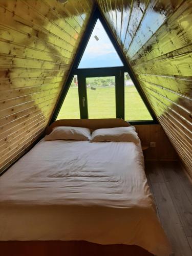 a bed in a room with a large window at Aframe Iza in Bradu