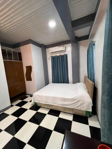 a bedroom with a bed and a checkered floor at Tiya Cheding Boarding House in Carolina