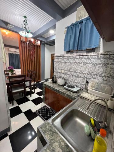 a kitchen with a sink and a checkered floor at Tiya Cheding Boarding House in Carolina